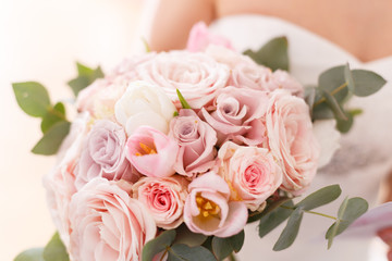 Brides bouquet of roses, tulips and eucalyptus, in her hands