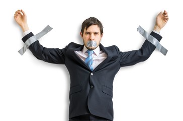 Businessman in suit is taped to the wall with adhesive tape. Isolated on white background.