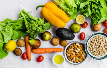 Flat lay photo of fresh fruit and vegetables, grains, and nuts on a white background. Concept of cooking and eating healthy food, fitness, vegetarian and vegan, and lifestyle.