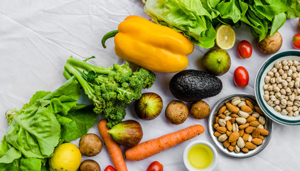 Flat lay photo of fresh fruit and vegetables, grains, and nuts on a white background. Concept of cooking and eating healthy food, fitness, vegetarian and vegan, and lifestyle.