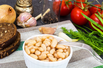 Canned beans with olive oil and garlic in white salad bowl