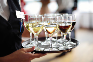 Waitress holding a dish of champagne and wine glasses at festive event