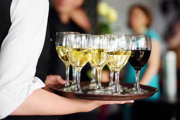 Waitress holding a dish of champagne and wine glasses at festive event