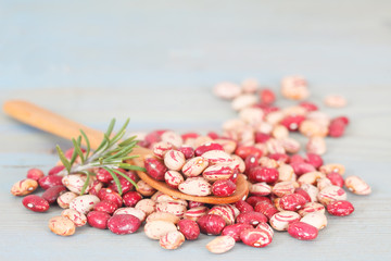 Pile of colorful beans with rosemary and wooden spoon. Healthy food.