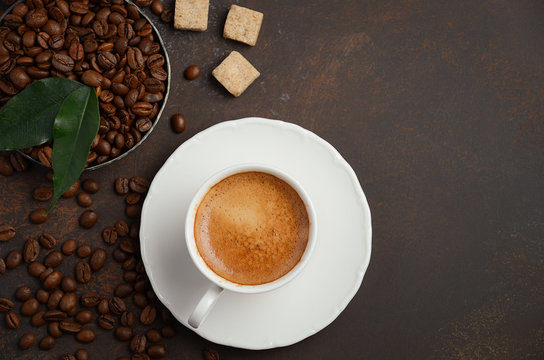 Cup of fresh coffee with coffee beans on dark background, top view, copy space