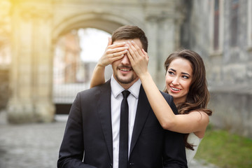 Beautiful brunette bride closed groom's eyes at wedding ceremony and smiling