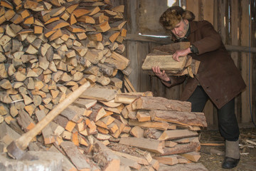 an elderly man in a cap with earflaps and felt boots firewoods holding hands