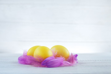 Yellow eggs with feathers on a white background. The concept of a happy Easter.