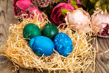 Fototapeta na wymiar Easter colored eggs, straw, flowers