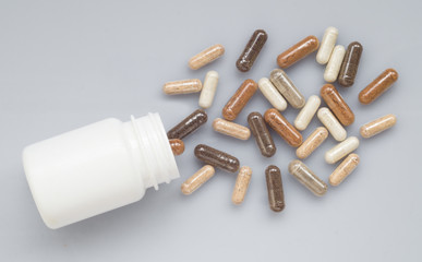 Naklejka premium Medicinal capsule spill out of a plastic bottle on a light surfa