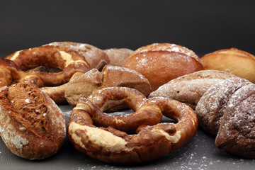 Different kinds of bread and bread rolls on board from above. Kitchen or bakery poster design.