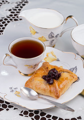 Cup of tea and cake on porcelain tableware for the white embroidered tablecloth