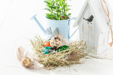 Colorful Easter eggs in nest and white birdhouse