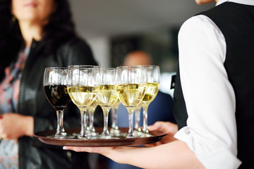 Waitress holding a dish of champagne and wine glasses at festive event