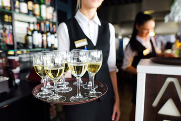 Waitress holding a dish of champagne and wine glasses at festive event