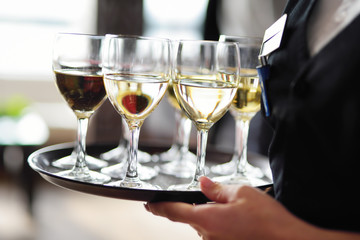 Waitress holding a dish of champagne and wine glasses at festive event