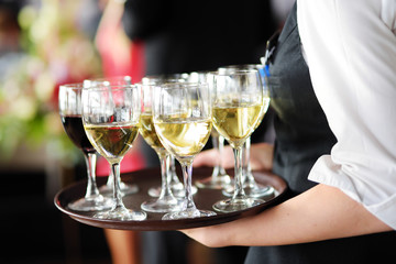 Waitress holding a dish of champagne and wine glasses at festive event