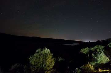 Milky way with trees over the Vilash Lake at Masalli with silhouette of hills. Nature of Azerbaijan