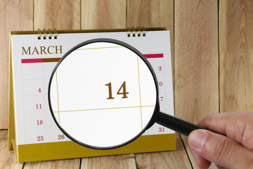 Magnifying glass in hand on calendar you can look fourteenth day of month,Focus number fourteen in March.
