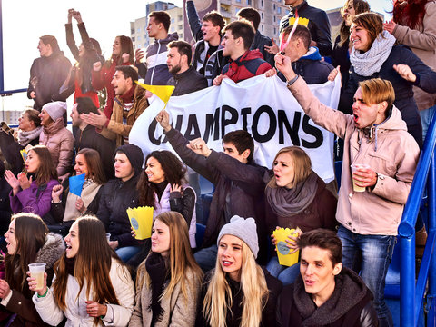 Fans cheering in stadium holding champion banner and singing on tribunes. Large group people together support your favorite team. People holding banner with Champion banner happily eating popcorn.