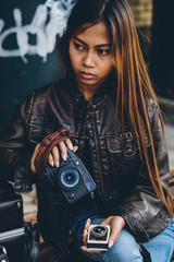 Beautiful hipster girl holding camera and light meter 