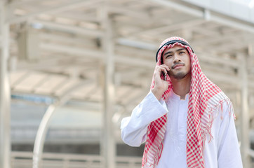 Fototapeta premium Young Arab businessman using mobile phone while walking in the city.