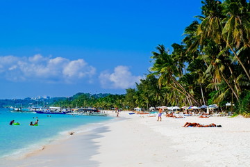 Beautiful tropical white sand beach with coconut palms and people on the beach