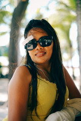 Happy portrait of Asian woman with sunglasses in summertime on the beach