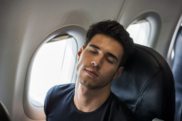 Side view of handsome young man against plane window sitting