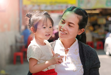 Asian woman and her daughter in Chinese dress against traditional chinese red decorations are very popular during the Chinese new year Festival at chinatown in bangkok, Thailand.