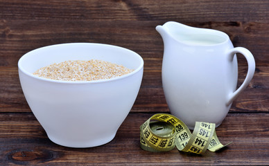 Bowl with oatmeal and pitcher with milk and centimeter