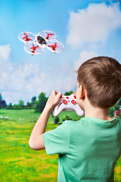 Happy boy drives toy quadcopter drone at nature landscape