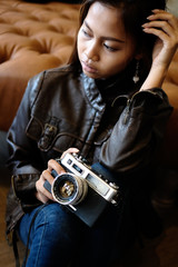 Cool hipster girl in a leather jacket holding camera