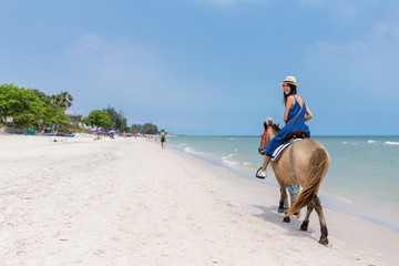 Woman riding horse on sand beach