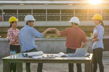 Fist Bumping Corporate Colleagues Teamwork between professional construction engineers after project complete at the sunset time, Industrial engineering and teamworks Concept, worm color tone