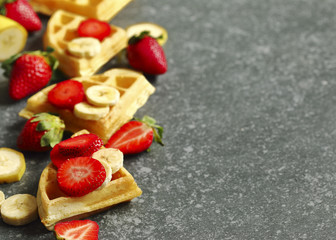 Belgian waffles with strawberries, banana and maple syrup