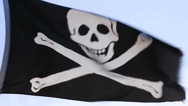 Looped footage features the pirate flag or Jolly Roger with skull and crossbones flying in a strong breeze. Looped with short fade at en