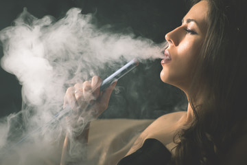 Young, beautiful girl smoke a hookah at club