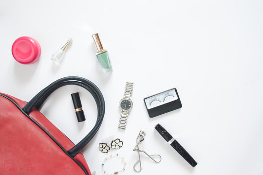 Flat lay of female items out of hand bag on white background