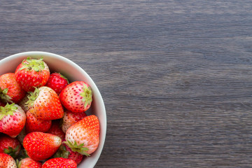 Fresh strawberry in cup on wooden background.
