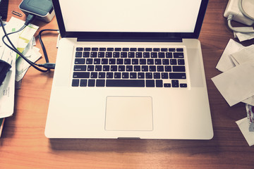 notebook or laptop computer on messy wooden desk