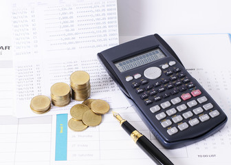 Calculator and money coins stack with fountain pen for finance concept