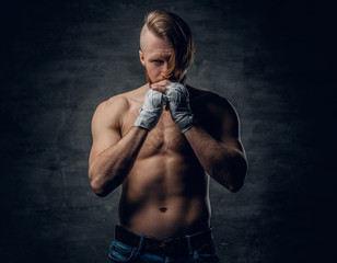Brutal fighter with long hair over dark grey background.