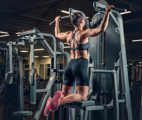 Fototapeta premium Female with short hair doing pull ups in a gym club.