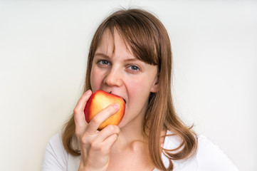 Woman eating an apple isolated on white