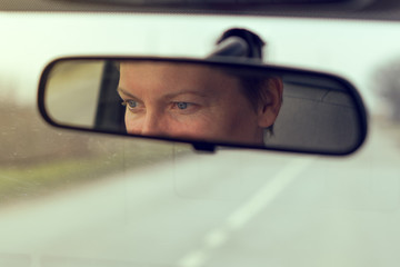 Female eyes focusing on road, reflection in vehicle rearview mirror