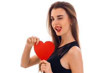 playful young brunette woman with red lips and heart in her hands posing isolated on white background