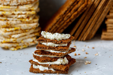 Sandwiches with curd cheese and bread roll for breakfast on a background stacks of various healthy crisp bread, diet, vitamin snack.