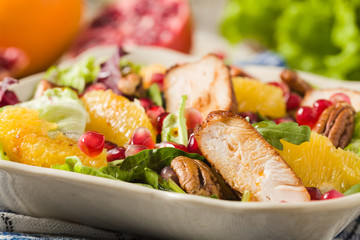 Spring salad with chicken, pomegranate, orange, pecan nuts and honey.