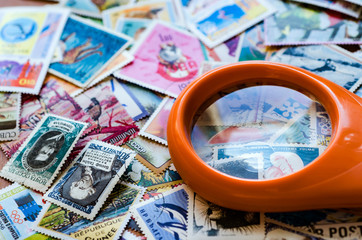 DZERZHINSK, RUSSIA - DECEMBER 16, 2016: Postage stamps of different countries and themes with a magnifying loupe